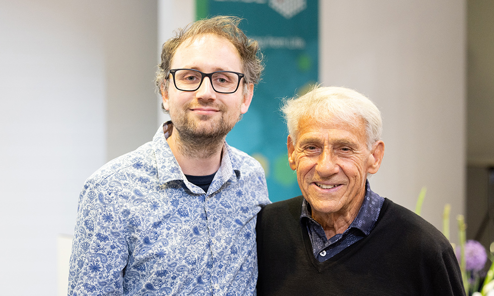 Two men stand side by side, a younger scientist with glasses on the left and an older benefactor on the right