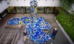 A man and woman stand alongside a colourful array of plastic boxes.