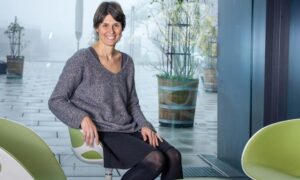 Female scientist in chair looking at camera.