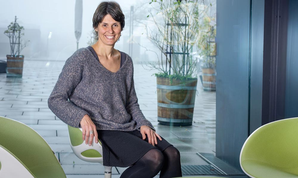 Female scientist in chair looking at camera.