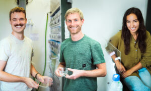 The image shows three young people smiling. The background of the image transport us to a scientific laboratory.