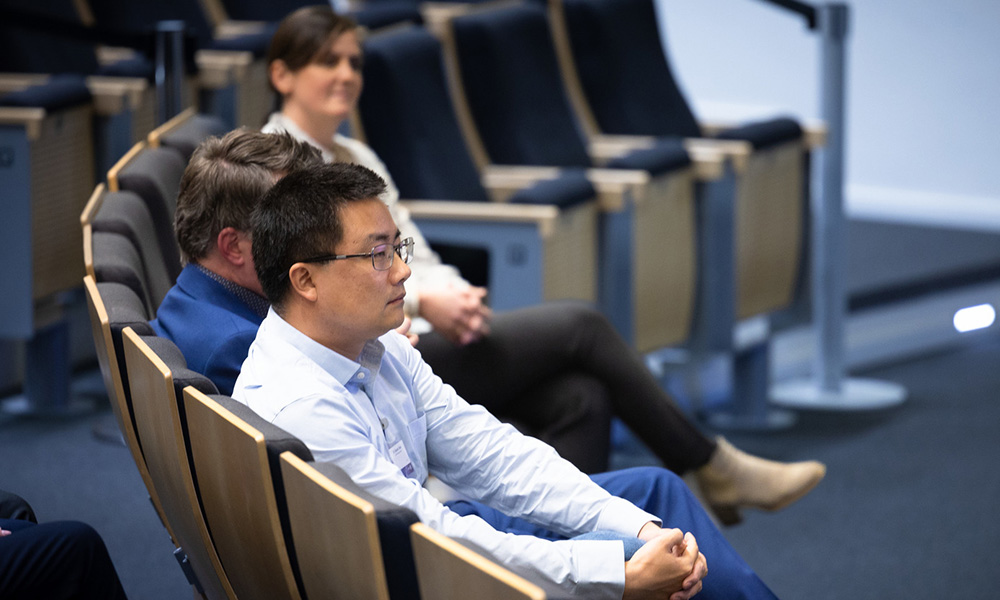 Three scientists sit in front row of auditorium